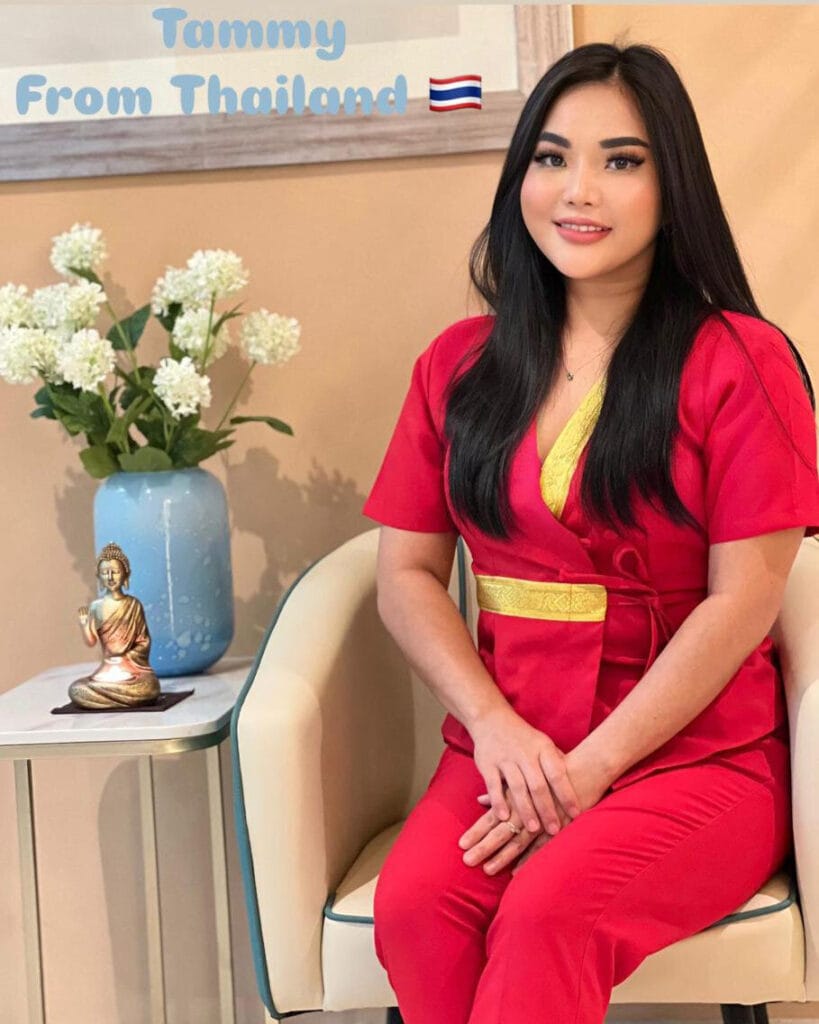 A woman in a red dress sits elegantly on a chair, showcasing her poise and grace in a refined setting.jpg