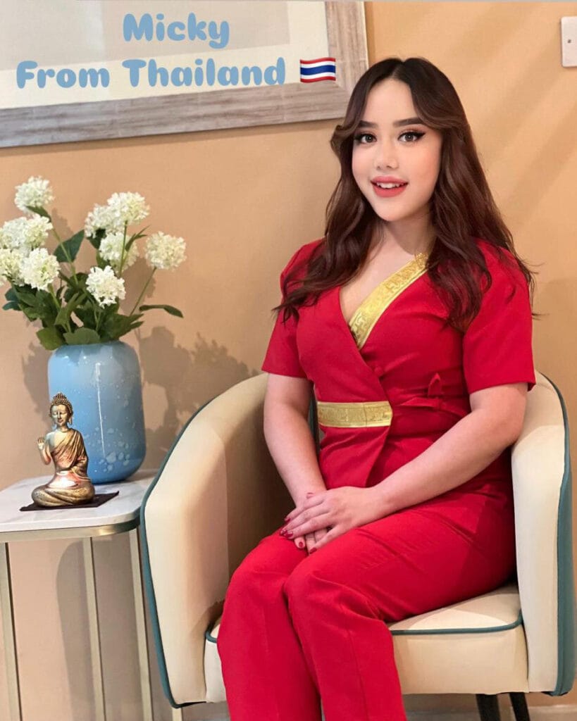 A woman in a red dress sits elegantly on a chair, showcasing her poise and grace in a refined setting.jpg